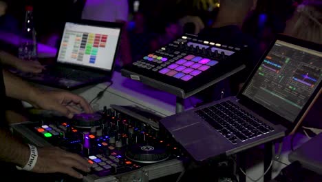 Nightclub-DJ-Mixing-Music-on-a-Turning-Table-with-Strob-Lights-and-a-Couple-on-the-Dance-Floor,-Slowmotion