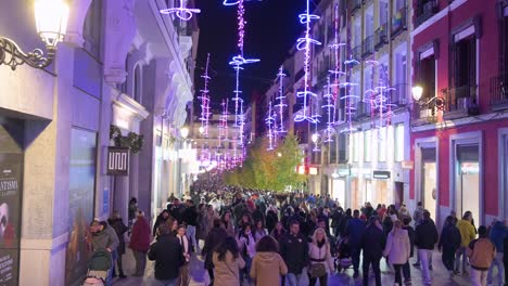 Menschen-Gehen-Während-Der-Weihnachtsfeiertage-Durch-Eine-überfüllte-Fußgängerzone,-Die-Mit-Weihnachtlichen-Violetten-Lichtern-Beleuchtet-Ist