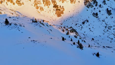 Circular-drone-footage-revealing-snowy-mountains-with-a-golden-sun-in-the-Pyrenees-mountains