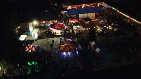 Illuminated-Christmas-fairground-festival-rides-in-neighbourhood-car-park-at-night-aerial-view