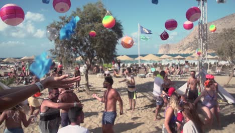 Fiesta-En-La-Playa-Vigilada-Por-Salvavidas-Con-Gente-Bailando-Y-Confeti-Arrojado-En-Creta,-Grecia,-Cámara-Lenta