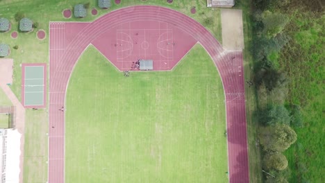 Top-Down-Aerial-View-of-Empty-Athletics-running-Track-on-a-Green-Field