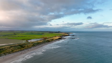 4K-Aerial-Seahouses-coastline-with-Bamburgh-Castle-off-in-the-distance-at-Sunset