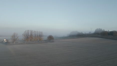 Remote-countryside-field-covered-in-mysterious-morning-fog,-dolly-forward