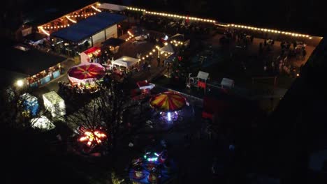 Beleuchteter-Weihnachtskirmes-Auf-Dem-Parkplatz-In-Der-Nachbarschaft-Bei-Nacht,-Luftaufnahme
