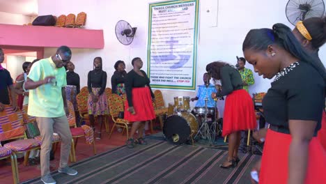 Afrikanische-Frau-Singt-Ins-Mikrofon,-Während-Andere-Bei-Einer-Gospelmesse-Tanzen