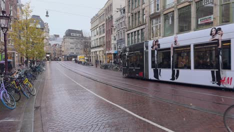 Tram-or-train-circulating-on-a-central-street-in-Amsterdam-and-a-cyclist-walking