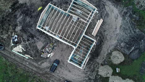 Construction-site-of-new-family-home-in-countryside-area-on-moody-autumn-day,-aerial-top-down-view