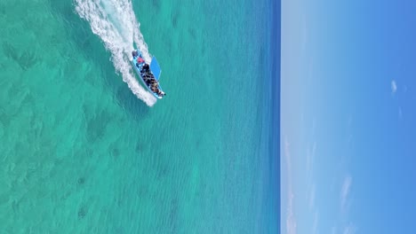 Vertical-drone-shot-of-speedboat-with-tourist-cruising-on-turquoise-Caribbean-sea-in-Dominican-Republic
