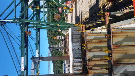 Container-crane-unloads-cargo-ship,-Panama-Canal-port,-vertical-video