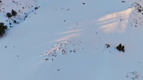 Kreisförmige-Drohnenaufnahmen-Von-Oben-Nach-Unten-Von-Schnee-In-Den-Bergen-Mit-Einer-Goldenen-Sonne-In-Den-Pyrenäen