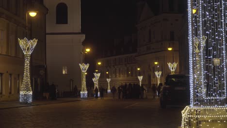 Weihnachtsbeleuchtungsdekoration,-Alte-Kopfsteinpflasterstraßen-Der-Altstadt-Von-Warschau,-Polen,-Mit-Menschen,-Die-Vorbeigehen