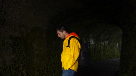 Man-inside-of-a-cave-of-Faial-Caldeira-touching-the-vegetation,-Azores