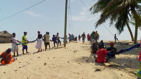 Eine-Gruppe-Afrikanischer-Menschen-Arbeitet-Zusammen,-Um-Die-Fischernetze-Am-Strand-Einzusammeln