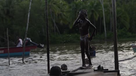 Una-Niña-Y-Varios-Niños-Se-Divierten-Jugando,-Saltando-Y-Nadando-En-La-Sabiduría-Local-Del-Distrito-De-Asmat,-Papua.