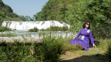 Weibliche-Touristin-Posiert-Für-Fotos-Vor-Wunderschönem-Wasserfallhintergrund