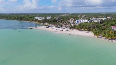 People-swimming-in-ocean-green-water,-Boca-Chica-beach-in-the-Caribbean,-aerial