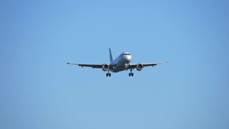 Aterrizaje-De-Avión-A-Reacción-Con-Fondo-De-Cielo-Azul,-Enfoque-De-Vista-Frontal