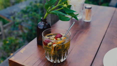 Herbal-tea-glass-cup-on-wooden-table-with-jar-of-flowers