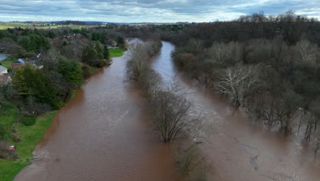 Luftaufnahme,-Die-Einen-überfluteten-Fluss-Mit-Schmutzigem-Wasser-Nach-Starkem-Regen-In-Den-Vororten-Der-USA-Zeigt