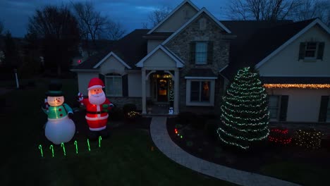 Inflatable-Santa-and-Frosty-the-Snowman-with-Christmas-light-decorations-at-two-story-American-home-during-holiday-season