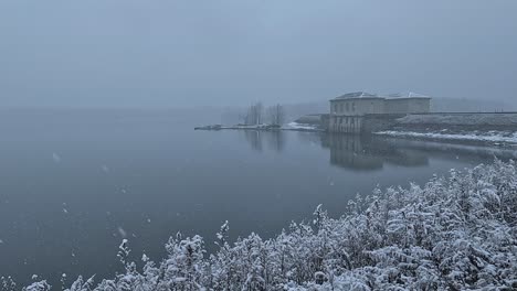 Heavy-snowfall-over-a-beautiful-reservoir-and-nearby-causeway-dam