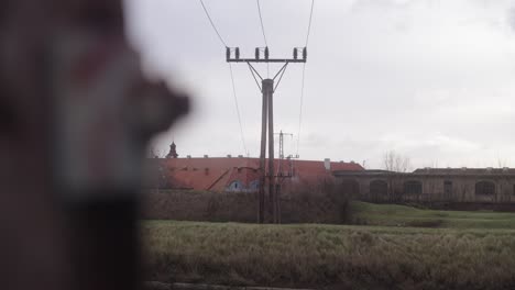 A-close-up-of-a-bolt-in-a-wooden-electric-pole-transitions-to-a-wide-shot-of-the-Terezín-Fortress