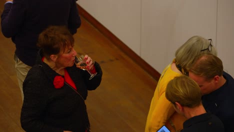 Top-down-view-on-red-haired-senior-lady-drinking-glass-of-wine-with-passers-by