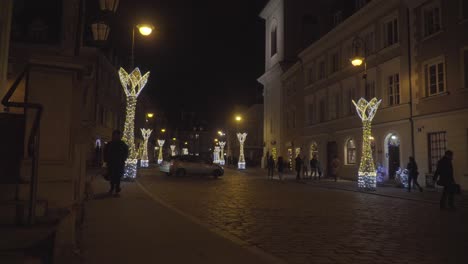 La-Gente-Camina-Por-La-Noche-En-Una-Calle-Europea-Adoquinada-Del-Casco-Antiguo-De-Varsovia,-Polonia