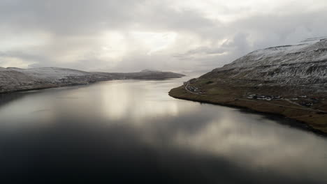 Färöer-Inseln,-4K-Luftaufnahme-Einer-Stadt-Am-Rande-Des-Wassers-Mit-Wunderschönen-Wolken--Und-Sonnenscheinreflexionen