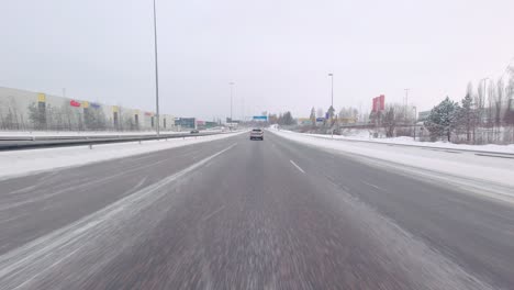 Car-driving-on-a-freeway-road-covered-with-snow