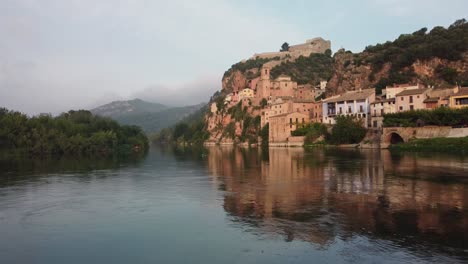 Drone-flight-over-Ebro-River,-view-of-Miravet-village-and-castle