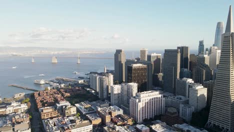 Soar-above-downtown-San-Francisco-with-this-aerial-video,-featuring-the-Bay-Bridge-and-the-city's-architectural-marvels-bathed-in-the-warm-glow-of-the-setting-sun