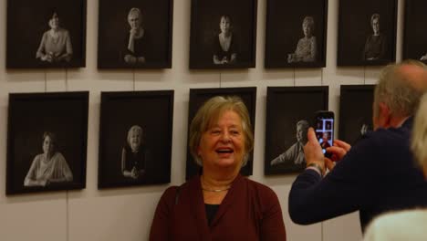 Ältere-Weiße-Dame-Posiert-Vor-Ihrem-Foto-Auf-Einer-Kunstausstellung
