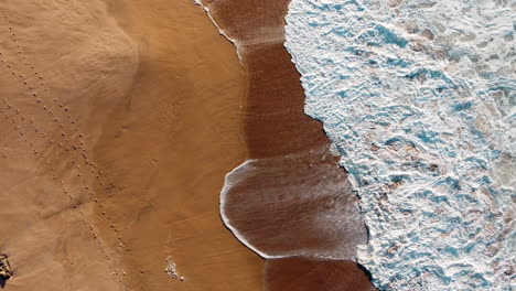 Drohnenansicht-Schöner-Sandstrand-In-Portugal,-Bild-Des-Musters,-Das-Durch-Weiße-Wellen-Entsteht,-Die-Auf-Die-Küste-Treffen