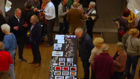 Top-down-view-on-white-senior-crowd-at-a-opening-reception-enjoying-art
