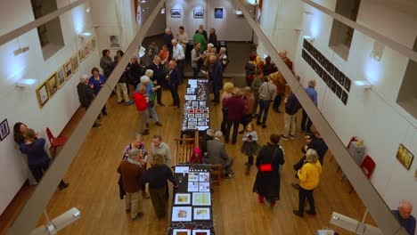 Top-down-view-on-interior-of-exhibition-space-with-crowd-of-people-and-art