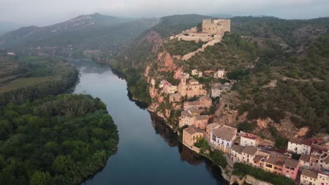 Drone-view-approaching-Miravet,-view-of-castle,-town-and-Ebro-river