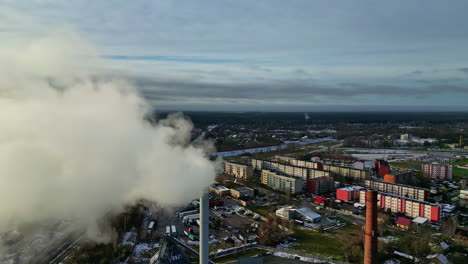Aerial-view-passing-a-smoking-factory-chimney-with-condos-in-the-background