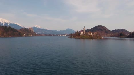 Smooth-drone-above-water-forward-low-flying-view-Bled-lake-island-church-in-winter