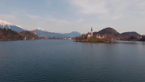 Schnelle-Drohne-über-Dem-Wasser-Nach-Vorne,-Niedrige-Flugansicht,-Bled-See-Insel-Kirche-Im-Winter