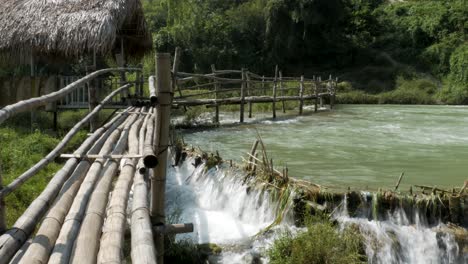 Wooden-bridge-spans-over-the-waterfall,-blending-harmoniously-with-nature