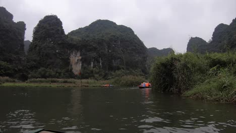 Row-boats-Ninh-Binh-Vietnam,-tourists-rowing-in-timelapse-going-into-cave-entrance