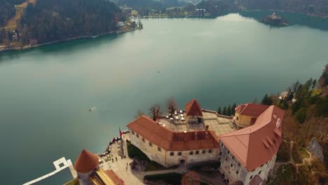 Drone-forward-flying-view-of-sunlit-lake-Bled-castle