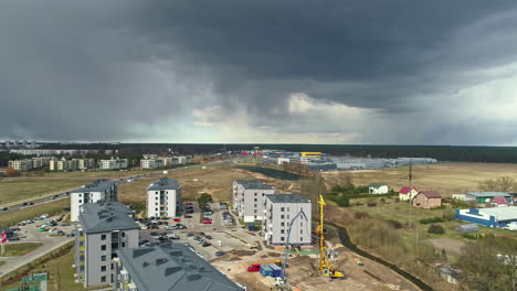 Apartment-Complex-Under-Construction-with-Dark-Gloomy-Clouds-Overhead,-Aerial-Reveal-Drone-Shot