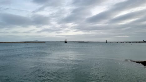 Holyhead-seascape-industrial-dredger-ship-entering-calm-overcast-breakwater-harbour