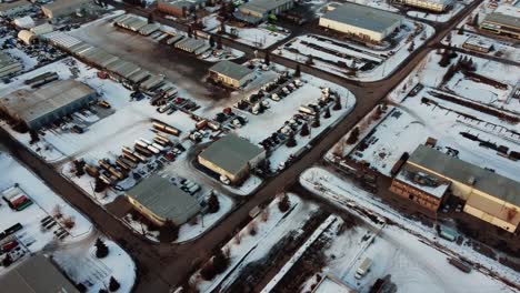 Aerial-shot-of-trucks,-trailers,-and-tanks-parked-in-an-outdoor-warehouse-in-winter