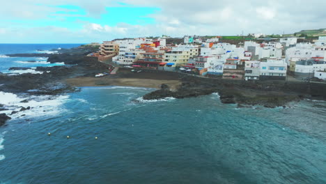 Cinematic-and-orbital-aerial-view-over-the-beach-and-coast-of-El-Puertillo-in-the-north-of-the-island-of-Gran-Canaria-and-with-large-waves-hitting-the-coast
