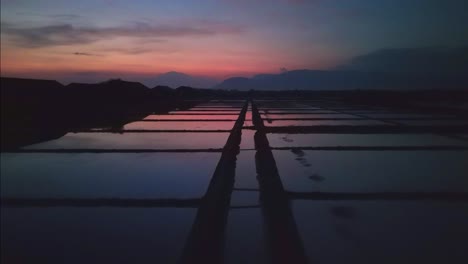 Salzfelder,-Spiegelnde-Flache-Reflexionen-Eines-Dunkelroten-Sonnenuntergangs