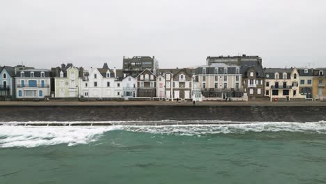 Aerial-Drone-Saint-Malo,-France-Ocean-Waves-Crashing-onto-Sea-Wall-on-a-Cloudy-Day
